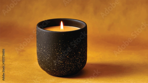 lit candle in black speckled container on golden surface