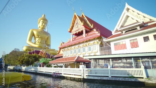 Big golden buddha statue river side with wooden boat sightseeing travel in Bangkok Thailand
