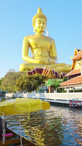 Big golden buddha statue river side with wooden boat sightseeing travel in Bangkok Thailand