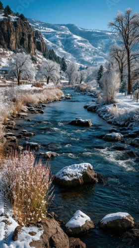 Winter river flows past snowy trees, rocks, and majestic mountains