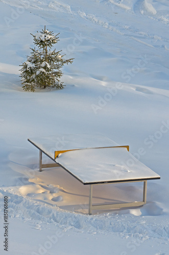 A tennis table under a thick layer of snow in a winter park