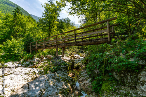Serene wooden bridge crossing Lepenjica River towards Sunik Waterfalls in Slovenias Soca Valley