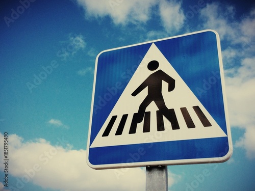 Looking up at a Pedestrian Crossing sign against a blue sky