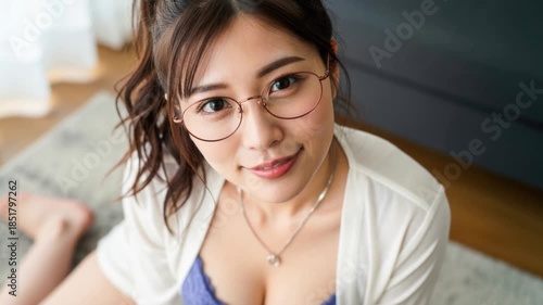 カーペットの上で眼鏡をかけた女性が笑顔で上を見つめる俯瞰カット