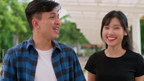 Joyful Friendship: A cheerful young man and woman, radiating genuine happiness, stroll together amidst a beautiful outdoor setting, sharing an intimate moment of connection and camaraderie.