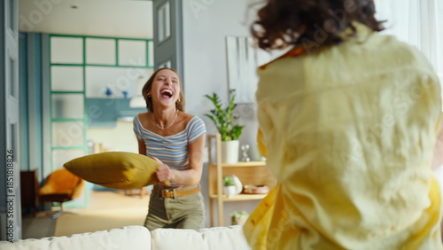Fényképezés Overjoyed girlfriends fighting pillows in comfortable living room