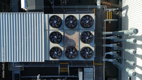 Aerial drone top down rotating view of cooling and ventilation systems on a data storage center warehouse building showing modern infrastructure.