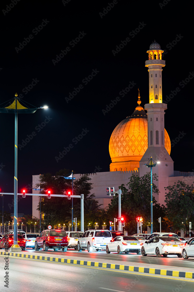 Fototapeta premium Sur, Oman - November 22,2025: Close-up Night View of the Distinctive Illuminated Dome and Minaret of Bahwan Mosque in Sur, Oman