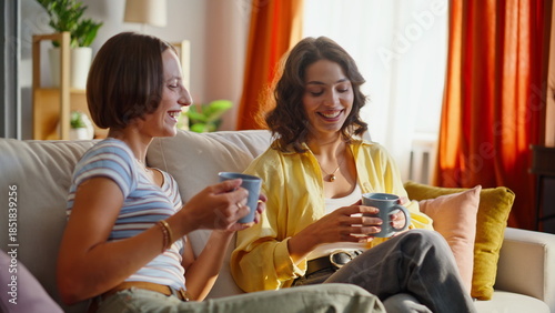 Fotografie Smiling ladies clinking coffee cups enjoying cozy domestic atmosphere closeup