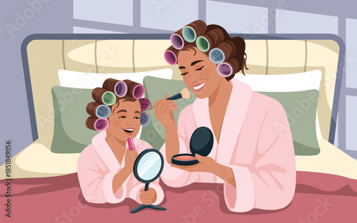Mother and daughter primping together in robes on a bed with hair curlers, having a bonding moment in a cozy bedroom setting.