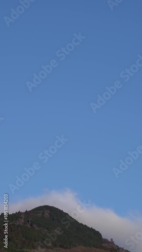 Winter peak of Mount Hiei in Kyoto with flowing clouds, and blue sky; Vertical; Video; Time-Lapse