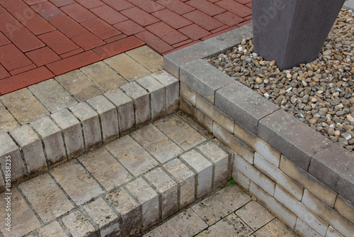 Photos Textured stone steps transition to a paved walkway, featuring a modern planter w