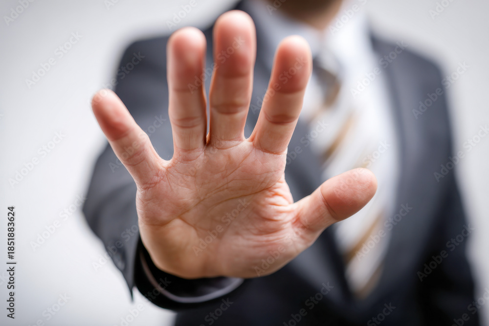 Obraz premium Businessman in suit extending hand towards camera with palm open expressing stop or halt gesture with blurred background and tie visible