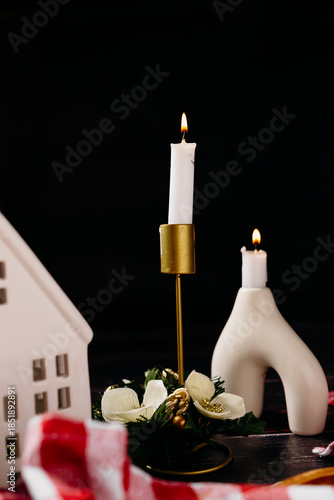 Minimal holiday still life with candle and ceramic house on dark background. Scandinavian Christmas decor and calm winter mood.