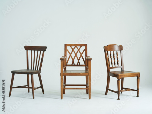 Three antique wooden chairs arranged against a white background
