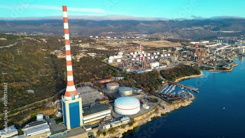 Aerial view of Urinj Thermal Power Plant on the Croatian Adriatic coast near Rijeka. Industrial architecture meets stunning natural landscape under a clear winter sky.