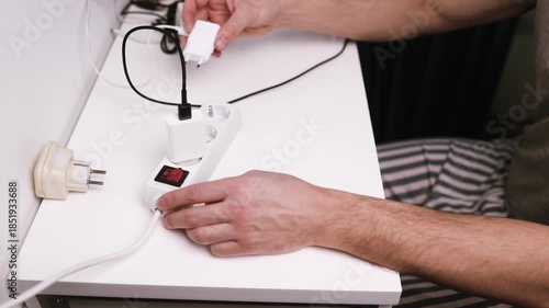 Close-up of male hand plugging a plug into a multiple socket