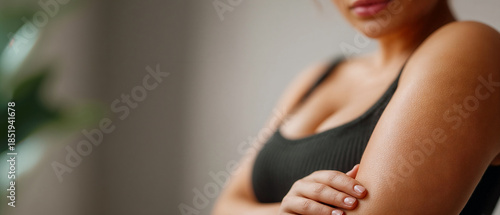 Young pump woman gently touching her arm while standing indoors  