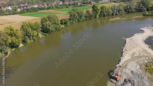 Aerial view of backhoes digging sand and gravel with shovels from the river by drone