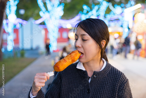 Wallpaper Mural Young woman enjoying corn dog at night market Torontodigital.ca