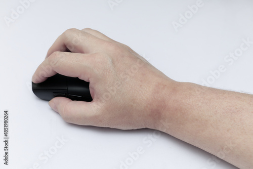 A close-up shot of a human hand operating a black wireless computer mouse on a clean white surface, highlighting office ergonomics and digital workflow