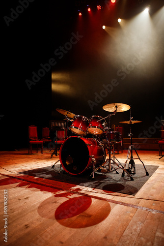 Red professional drum set on stage under dramatic theater spotlights