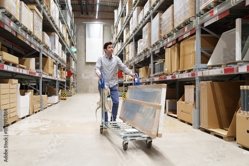 Man pushing cart with furniture in warehouse aisle. shopping, renovation, DIY