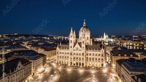Ornate illuminated neo-Gothic parliament building overlooks a bustling city square at night