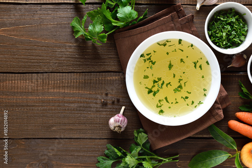 Chicken broth in bowl over wooden background