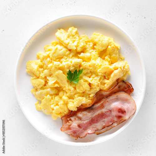 Scrambled eggs and fried bacon on plate