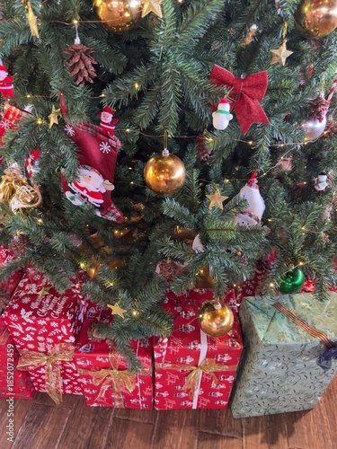 Traditional Christmas Tree Detail: A close-up view of the middle section of a Christmas tree decorated traditionally with red ornaments, golden baubles, and silver stars.