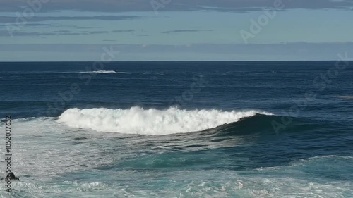 Powerful Atlantic Ocean wave breaking offshore near Porto Moniz on the north coast of Madeira Island, Portugal. Deep blue water, white sea foam, and rolling swell illustrate the raw energy of the open