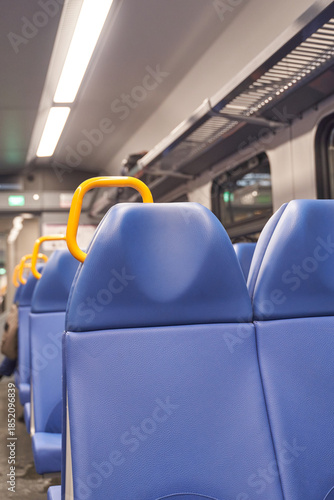 Empty blue seats with orange handles on modern train reflecting urban travel and daily commuting experience.