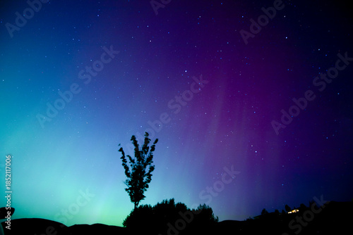 Northern lights with lots of purple and green lights shining above house on the hill