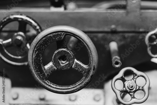 Industrial machinery showcasing detailed gears and valves in black and white, capturing the essence of vintage engineering in a workshop setting