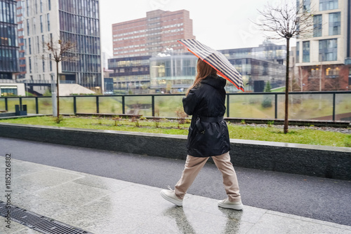 Photography Crossing pedestrian carries umbrella on rainy urban sidewalk