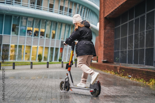 Moving electric scooter along wet street during rainy commute. Leaning into turn for micromobility transport. Urban mobility ride continues on slippery pavement in bad weather. Last mile travel.