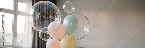 Bouquet of large translucent soap bubbles shaped like balloons floating in minimalist living room - Concept of Surreal Silliness  