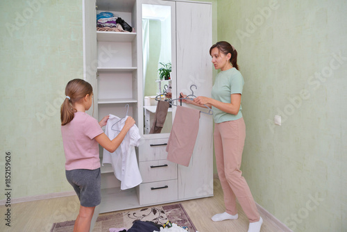 Mother and daughter sorting clothes in a cozy room.