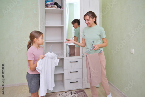 Mother and daughter sorting clothes in a cozy room.