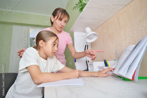 Mother helping daughter to complete school tasks.
