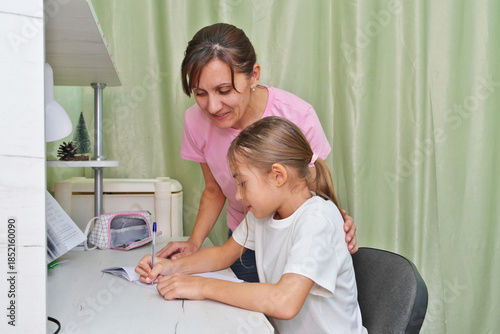 Mother helping daughter to complete school tasks.