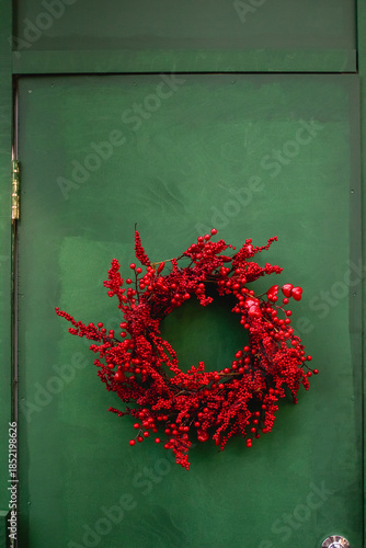 Christmas wreath of red berries on green door. A New Year's winter banner. Selective focus, space for text