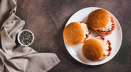 Burgers with grilled sausage and coleslaw on a plate top view web banner