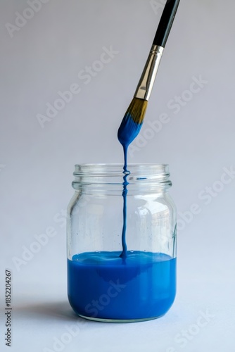 Close-up of blue pigment dispersing in water from artist's brush, creating fluid abstract patterns. Perfect for ASMR art channel content, paint product advertising, relaxation app visuals, color theor