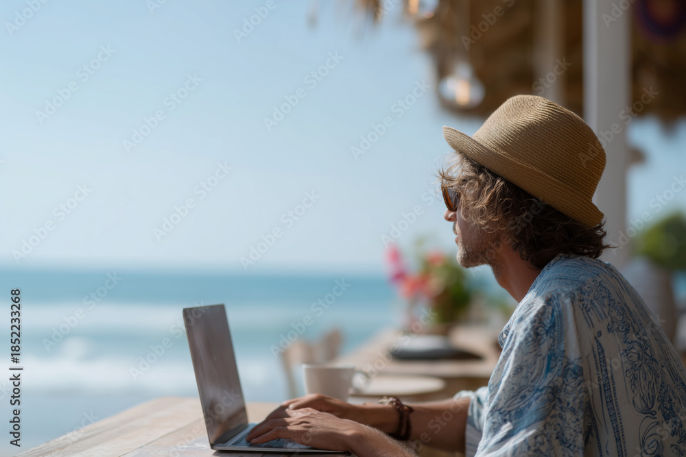 Fototapeta premium A man is sitting at a table with a laptop and a cup of coffee
