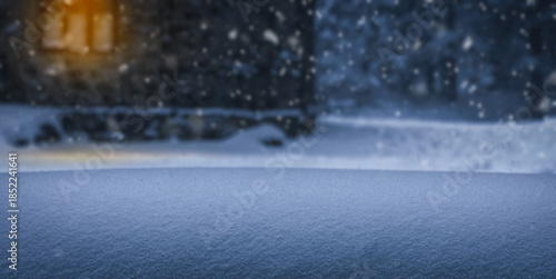 Snowfall over snowy yard with warm window