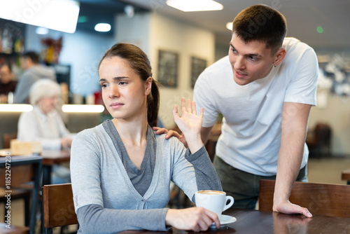 Girl rejects guy. Young man violates personal boundaries of female cafe visitor, distracts her. Girl pushes away annoying guy