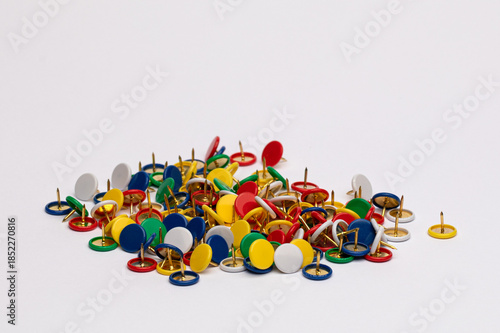 Multicolored pushpins scattered on a white background