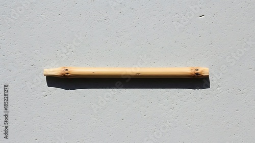 Minimalistic bamboo stick resting on a textured gray surface under sunlight